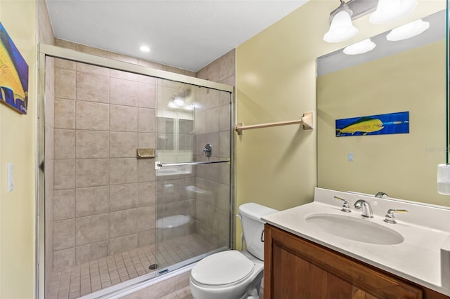 bathroom featuring a shower with shower door, toilet, and vanity