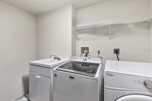 clothes washing area with cabinets, sink, and independent washer and dryer