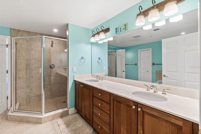 bathroom with a shower with door, vanity, and tile patterned flooring