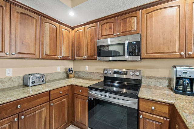 kitchen with tile patterned floors, light stone counters, and stainless steel appliances