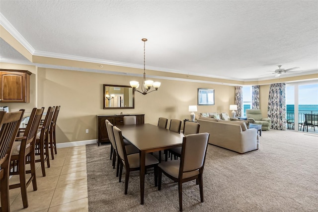 dining room featuring a water view, light tile patterned flooring, a textured ceiling, ornamental molding, and ceiling fan with notable chandelier