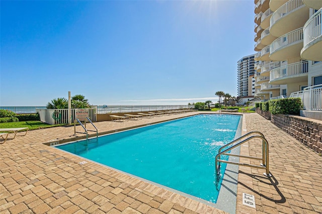 view of swimming pool featuring a view of the beach, pool water feature, and a water view