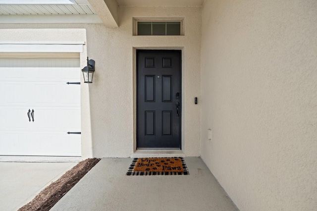 doorway to property featuring a garage and stucco siding