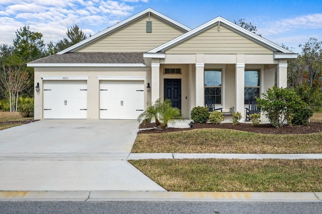 view of front of property featuring a shingled roof, a porch, stucco siding, a garage, and driveway