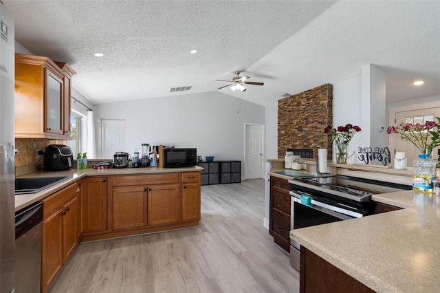 kitchen with stainless steel appliances, tasteful backsplash, light hardwood / wood-style floors, a textured ceiling, and vaulted ceiling