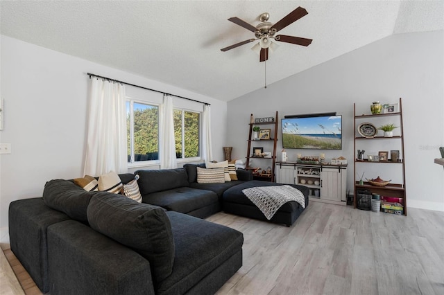 living room featuring ceiling fan, vaulted ceiling, a textured ceiling, and light wood-type flooring