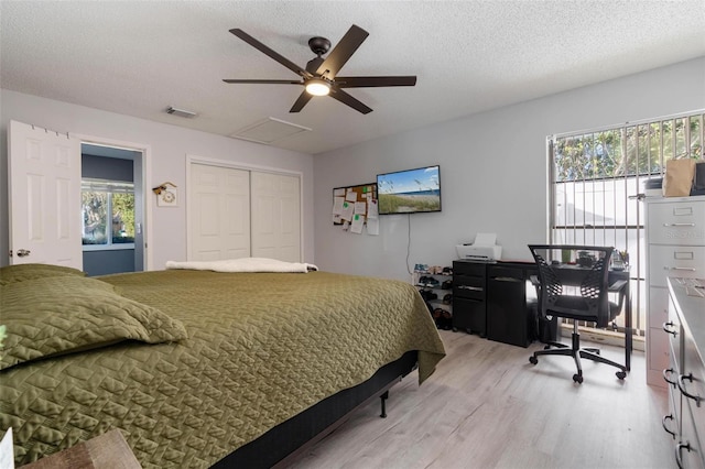 bedroom with ceiling fan, a textured ceiling, a closet, and light hardwood / wood-style flooring