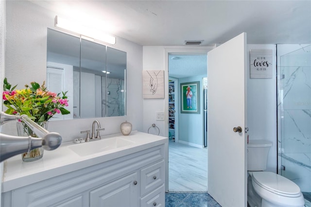 bathroom with a shower with door, vanity, and toilet