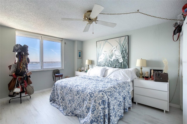 bedroom with ceiling fan, light hardwood / wood-style flooring, and a textured ceiling