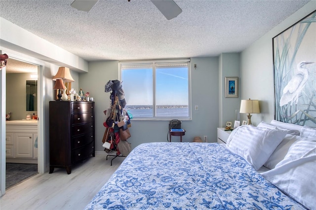 bedroom featuring connected bathroom, ceiling fan, light hardwood / wood-style flooring, and a textured ceiling