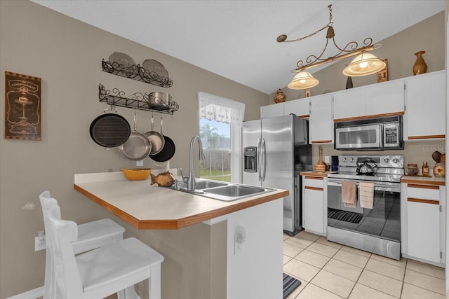 kitchen featuring white cabinetry, stainless steel appliances, a kitchen breakfast bar, hanging light fixtures, and sink