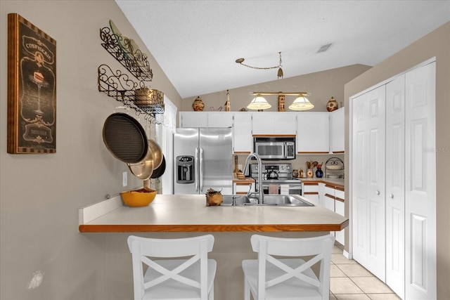 kitchen with white cabinets, vaulted ceiling, and appliances with stainless steel finishes