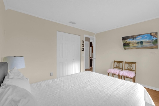 bedroom with a closet, hardwood / wood-style flooring, and ornamental molding