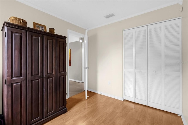 unfurnished bedroom with crown molding, light hardwood / wood-style flooring, and a closet