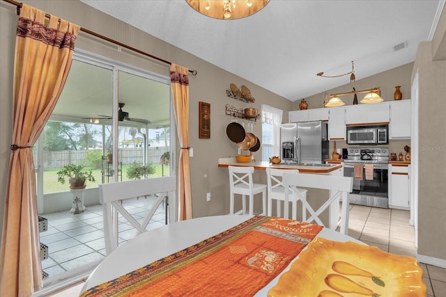 dining area featuring ceiling fan, light tile patterned floors, and lofted ceiling