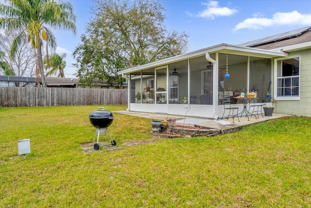 rear view of house with ceiling fan, a sunroom, a yard, and a patio