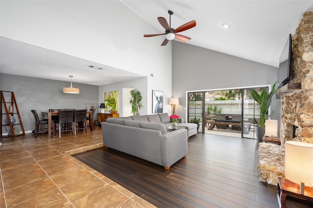 living room with a fireplace, high vaulted ceiling, and ceiling fan