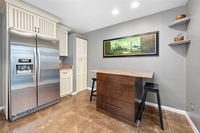 kitchen with stainless steel fridge, a breakfast bar area, and cream cabinets