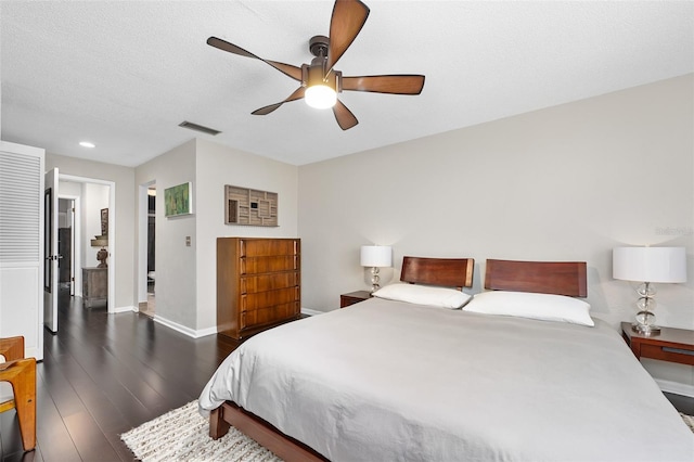 bedroom with a textured ceiling, ceiling fan, and dark hardwood / wood-style flooring