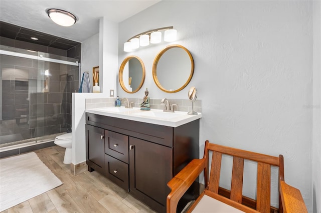 bathroom featuring vanity, toilet, and a shower with shower door