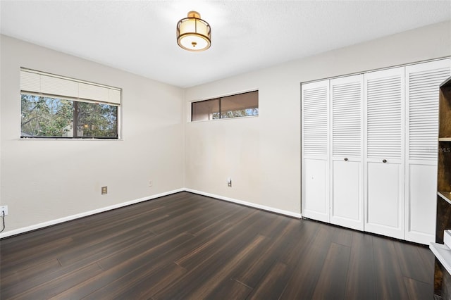 unfurnished bedroom with dark hardwood / wood-style floors and a closet