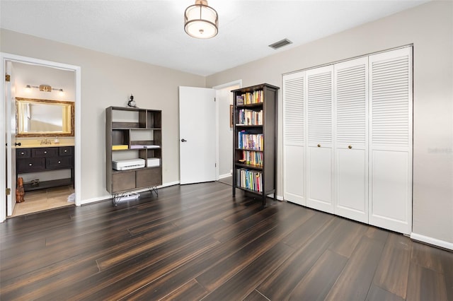 bedroom featuring connected bathroom, a closet, and dark hardwood / wood-style flooring