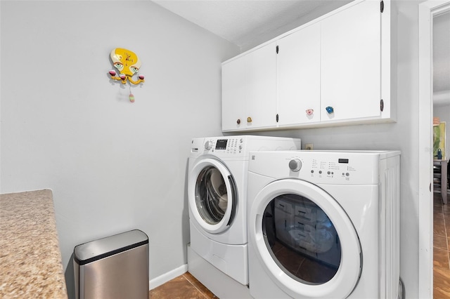 laundry area featuring cabinets, tile patterned floors, and washing machine and clothes dryer