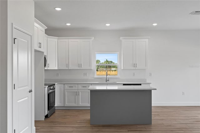 kitchen with a center island, hardwood / wood-style floors, white cabinets, sink, and stainless steel range with electric cooktop