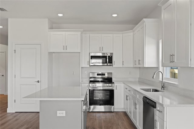 kitchen with white cabinets, stainless steel appliances, a center island, and sink