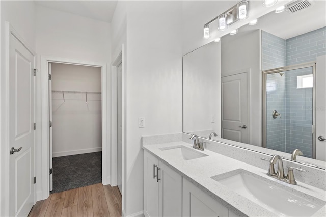 bathroom featuring wood-type flooring, a shower with shower door, and vanity