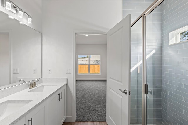 bathroom featuring a shower with door and vanity