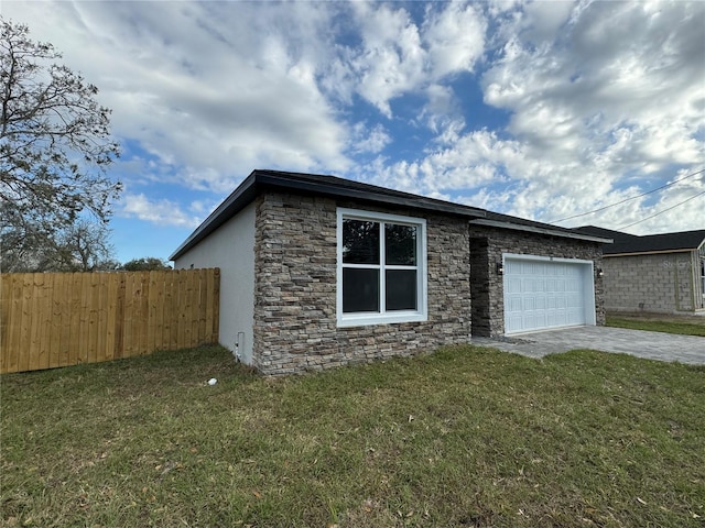 view of side of home featuring an attached garage, fence, concrete driveway, stone siding, and a lawn