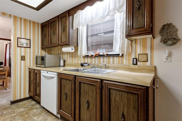 kitchen with sink, dishwasher, and dark brown cabinets