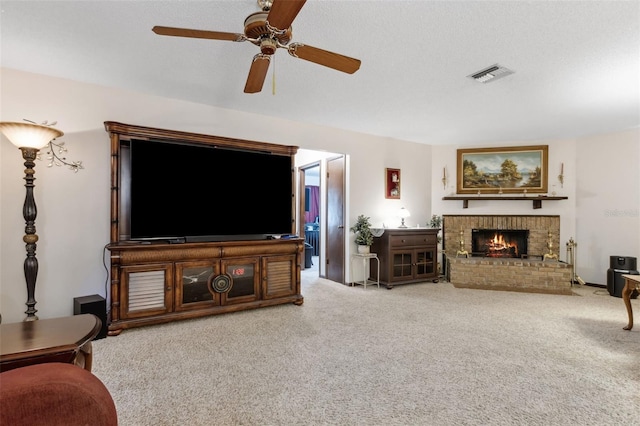 living room with ceiling fan, a brick fireplace, a textured ceiling, and carpet