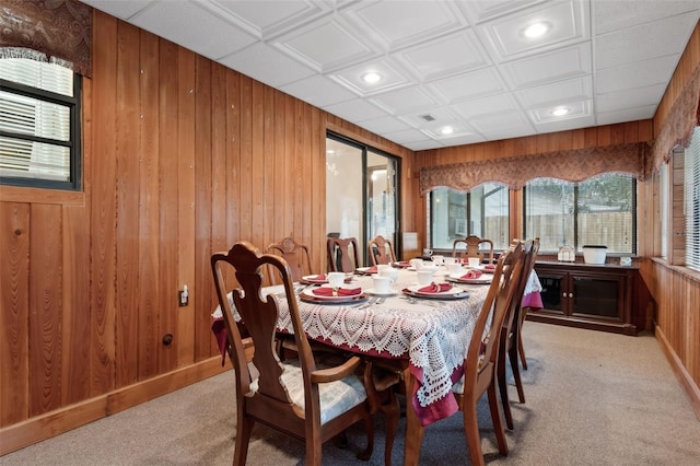 dining space featuring wood walls and light colored carpet