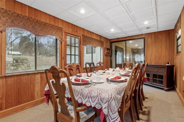 dining space with light colored carpet and wooden walls