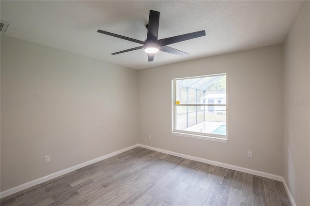 spare room featuring visible vents, baseboards, ceiling fan, wood finished floors, and a textured ceiling