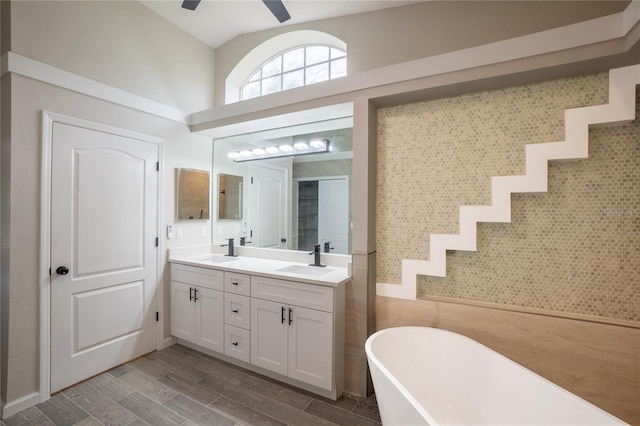 bathroom with ceiling fan, a soaking tub, a sink, and double vanity