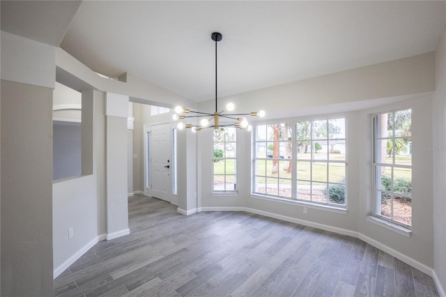 unfurnished dining area featuring a healthy amount of sunlight, a notable chandelier, and wood finished floors