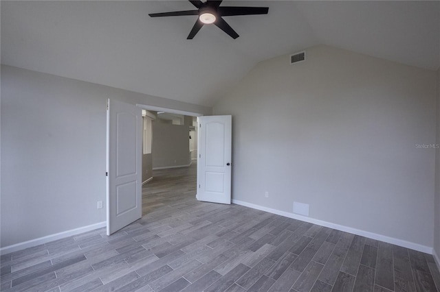 unfurnished room featuring visible vents, a ceiling fan, vaulted ceiling, wood finished floors, and baseboards