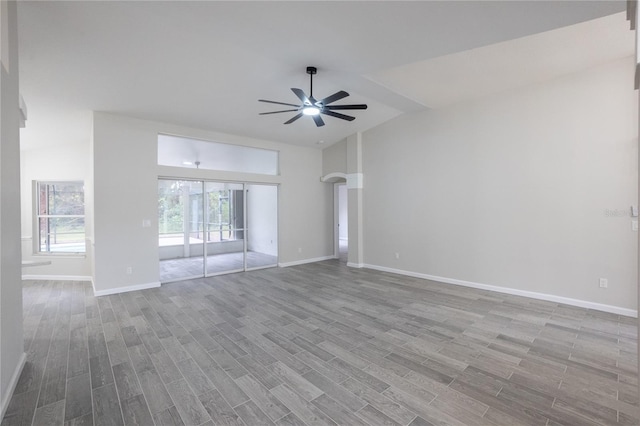 unfurnished living room with light wood finished floors, ceiling fan, baseboards, and vaulted ceiling