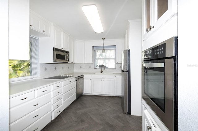 kitchen with white cabinetry, hanging light fixtures, decorative backsplash, dark parquet floors, and stainless steel appliances