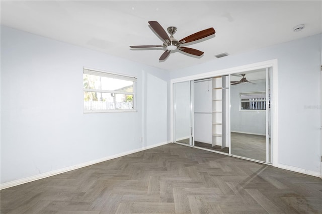 unfurnished bedroom featuring dark parquet floors, a closet, and ceiling fan