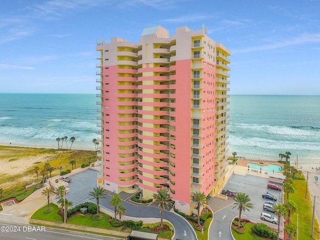 view of building exterior featuring a water view and a beach view