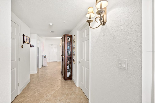 hallway featuring light tile patterned floors and a textured ceiling