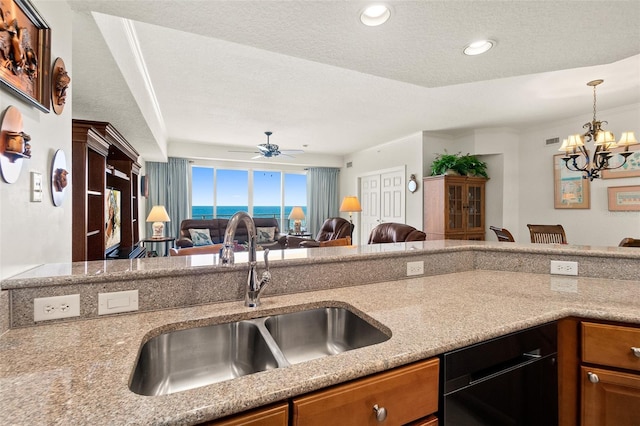 kitchen featuring sink, dishwasher, hanging light fixtures, light stone counters, and a textured ceiling