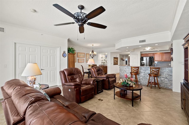 living room with ornamental molding, ceiling fan with notable chandelier, light tile patterned flooring, and a textured ceiling