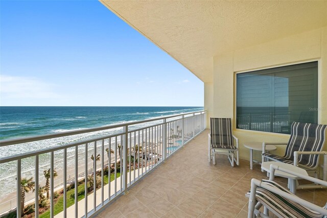 balcony featuring a water view and a beach view