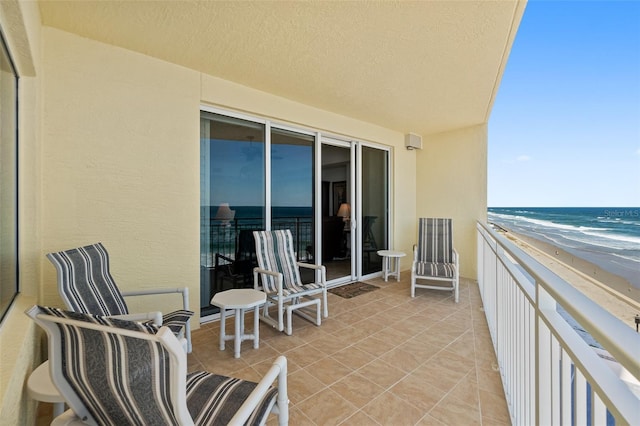 balcony with a water view and a view of the beach