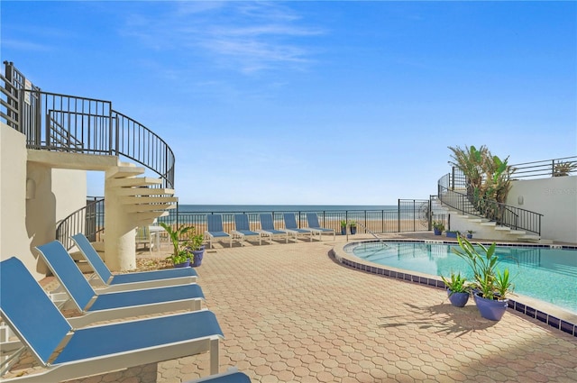 view of pool with a patio and a water view